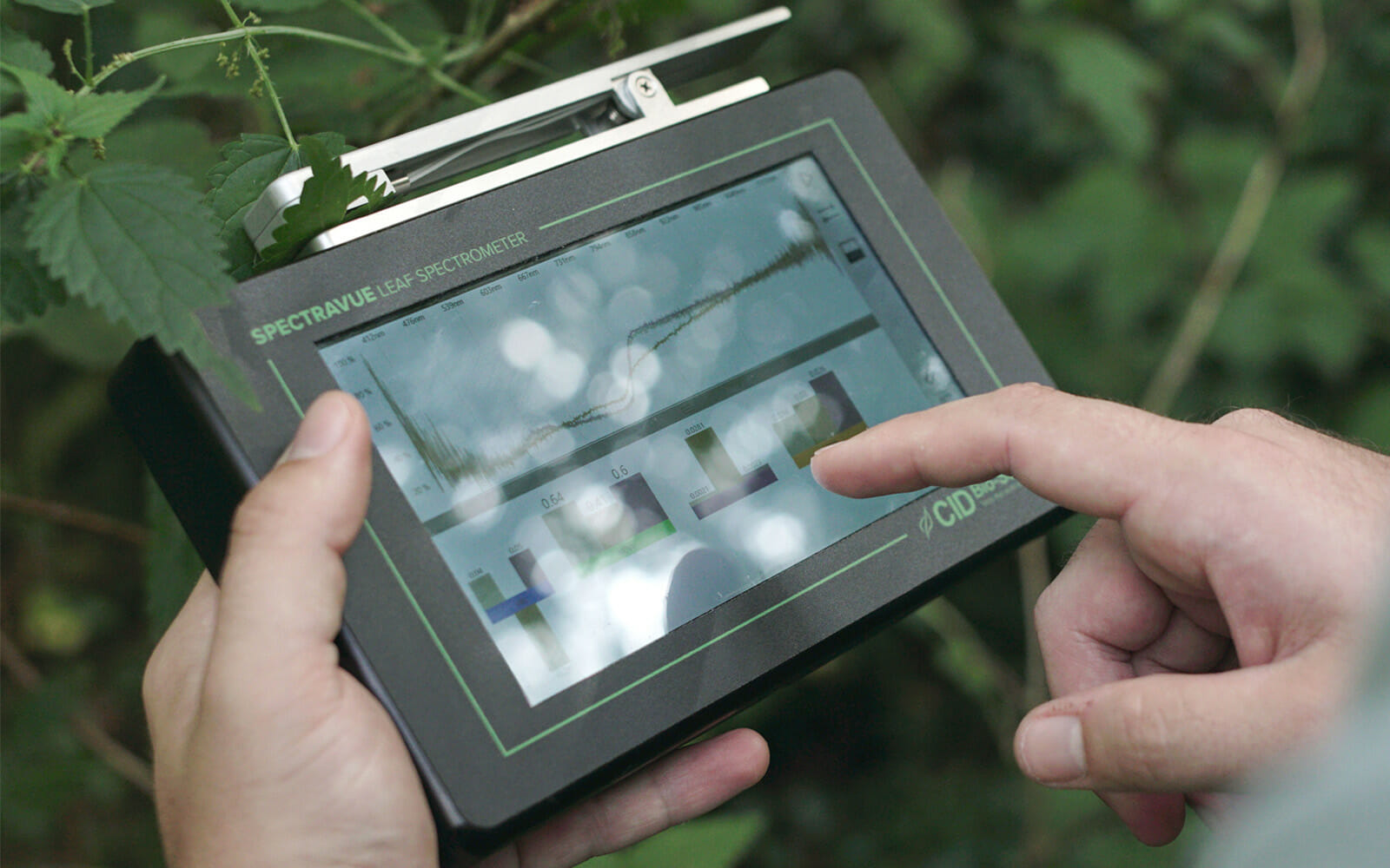Hands manipulating SpectraVue Leaf Spectrometer touch screen